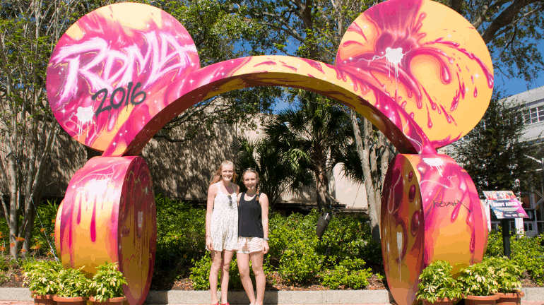 Guests enjoy the lively spirit beneath a vibrant Radio Disney “Roma 2016” arch, echoing classic Disney park celebrations.