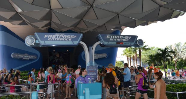 Guests line up beneath the Spaceship Earth geodesic dome at Epcot, ready to enter with FastPass+ and Standby lines visible.