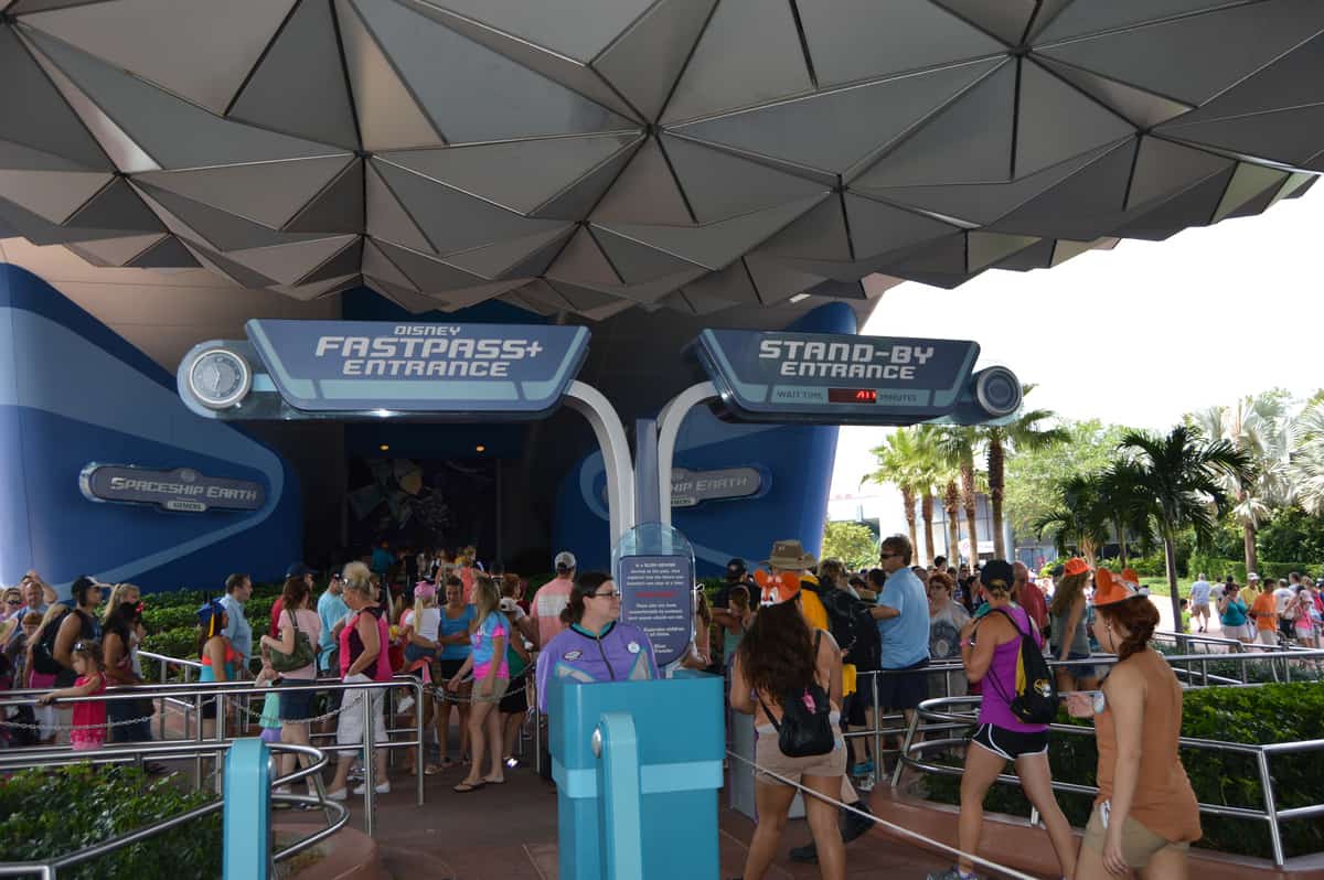 Guests line up beneath the Spaceship Earth geodesic dome at Epcot, ready to enter with FastPass+ and Standby lines visible.