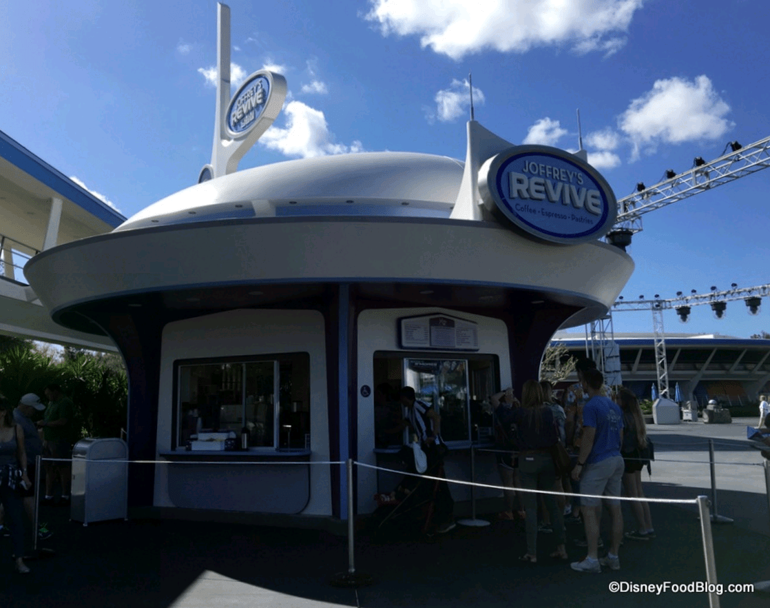 Joffrey’s Revive coffee kiosk in Tomorrowland draws a crowd under bright skies at Walt Disney World.