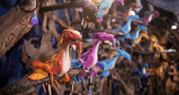 Pandora’s Banshee Connect dragon puppets perch on branches in a shop, with Disney World’s magic blurred in the backdrop.