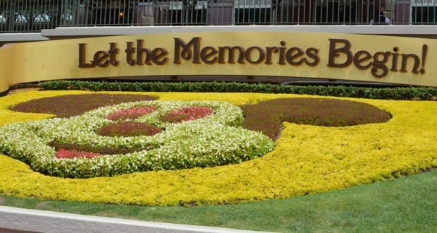 Mickey Mouse-shaped flower bed with a "Let the Memories Begin!" sign welcomes guests to Disney World magic.