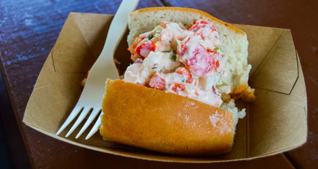 Lobster roll in a paper tray with creamy filling and a plastic fork, ready for your Disney Dining Plan adventure at Walt Disney World.