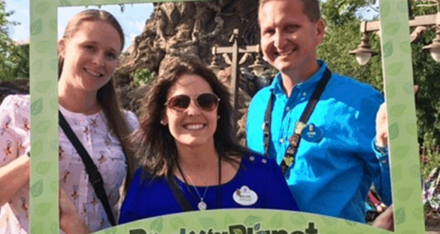 Guests smile behind a Party for the Planet frame at Disney's Animal Kingdom, celebrating Earth Day with PhotoPass excitement.