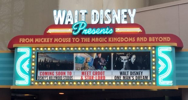 Walt Disney marquee aglow in neon, showcasing posters for new and fan-favorite park attractions with classic Disney characters.