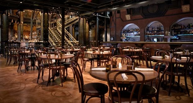 Cozy, softly lit Disney World restaurant with round tables, wooden chairs, and a well-stocked bar—ideal for theme park dining pros.