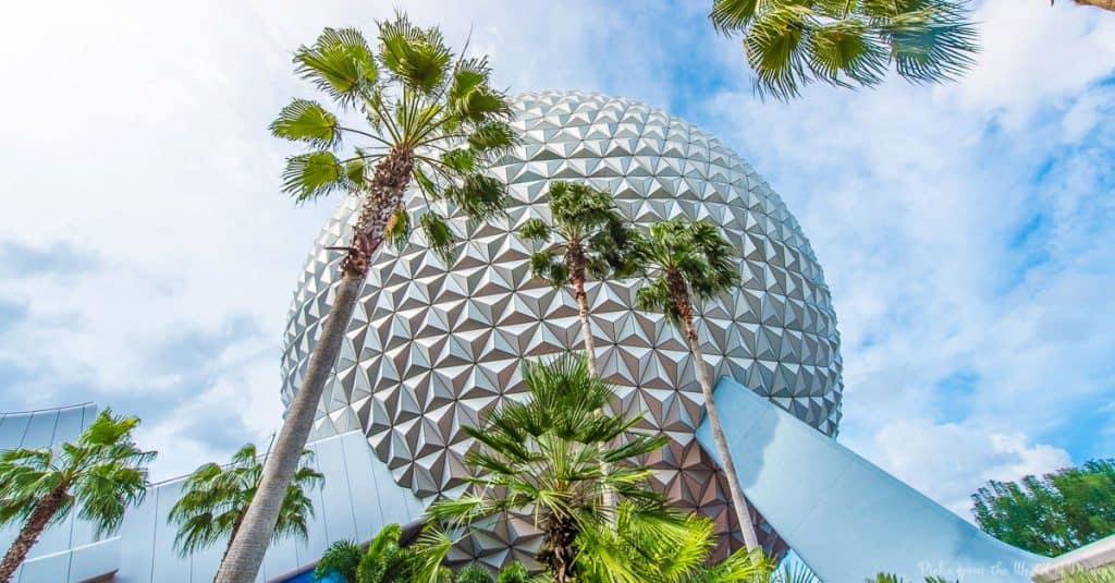 Spaceship Earth at Epcot rises above palm trees under a partly cloudy sky, capturing the magic of Walt Disney World adventure.