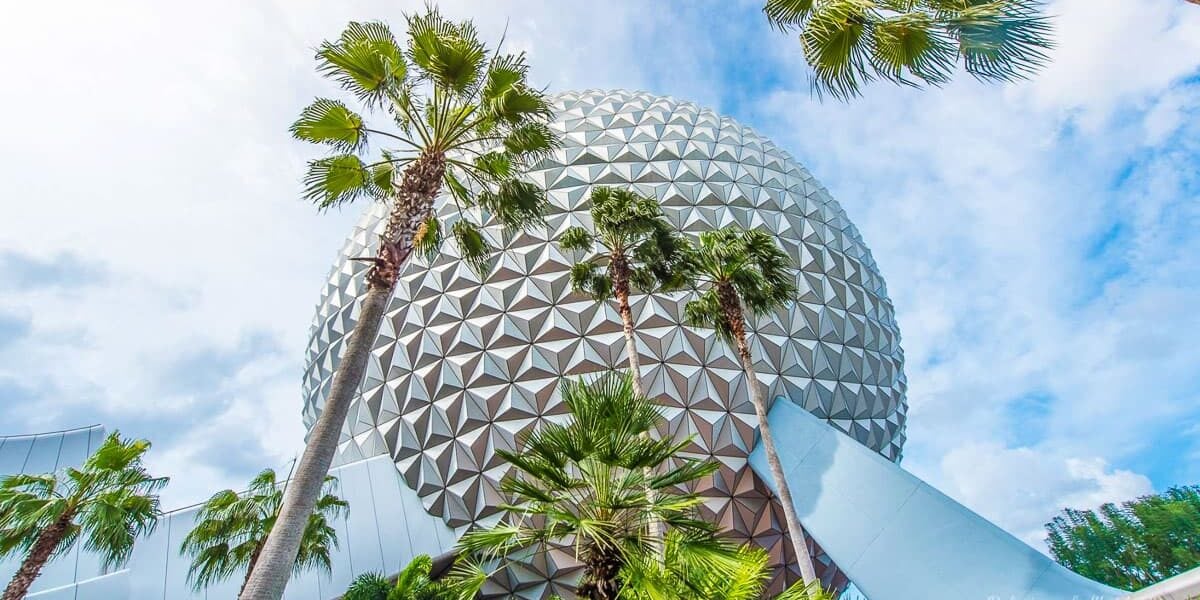 Spaceship Earth at Epcot rises above palm trees under a partly cloudy sky, capturing the magic of Walt Disney World adventure.