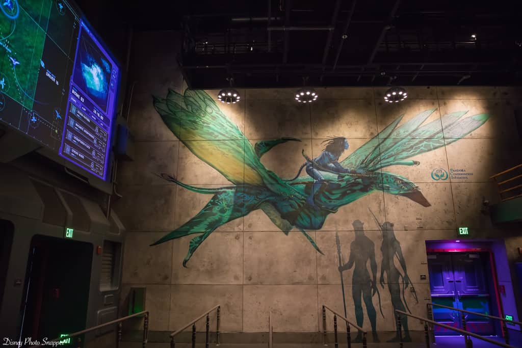 A mural of a guest riding a banshee inside Pandora – The World of Avatar at Disney's Animal Kingdom, with queue barriers visible.