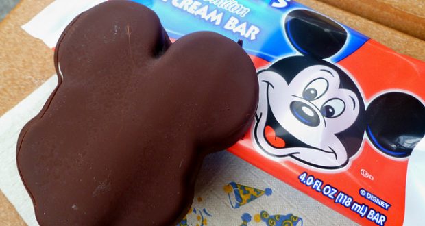 Mickey-shaped chocolate ice cream bar next to its bright Mickey wrapper—a must-try Disney World snack for every fan.