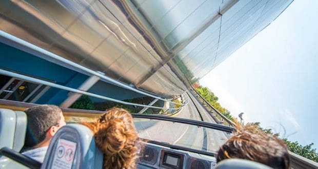 Guests race along an outdoor track in a sleek ride vehicle, zipping past gleaming metal walls in true Disney World thrill-ride style.