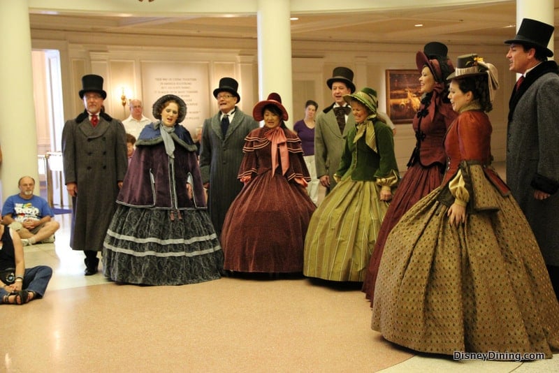 Carolers in 1800s attire perform inside EPCOT, delighting guests and spreading holiday cheer throughout the park.