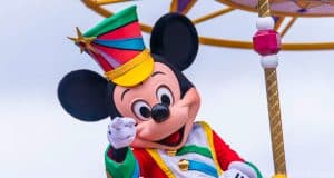 Mickey Mouse dazzles in vibrant parade attire, beaming and waving to fans at Walt Disney World—an unforgettable magical moment!.