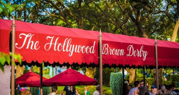 The iconic Hollywood Brown Derby red canopy at Disney’s Hollywood Studios, bustling with guests beneath lush trees.