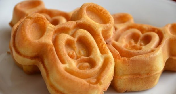 Mickey-shaped golden waffles served on a white plate, a classic Disney Parks breakfast favorite.