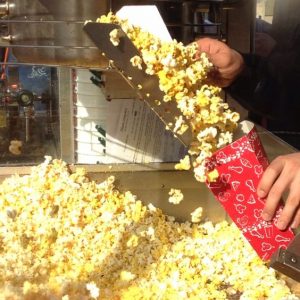 Fresh popcorn pours into a classic red Disney container—grab this fan-favorite snack on your next magical park adventure!.