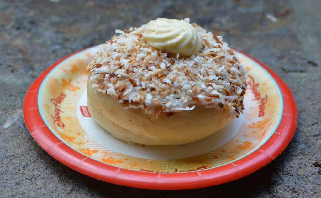 Delicious donut with toasted coconut and cream on a Disney Parks plate—a fan-favorite snack for savvy Disney visitors.