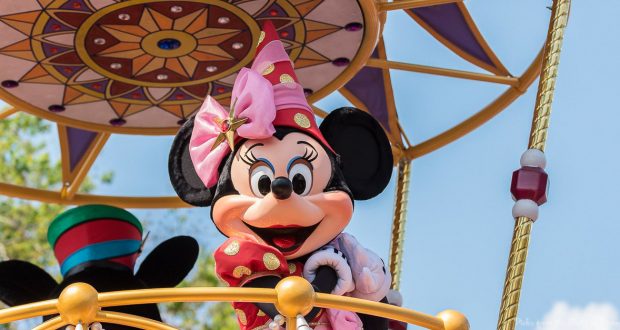 Minnie Mouse greets fans from a sparkling gold and purple float, dazzling crowds at Magic Kingdom's lively parade.