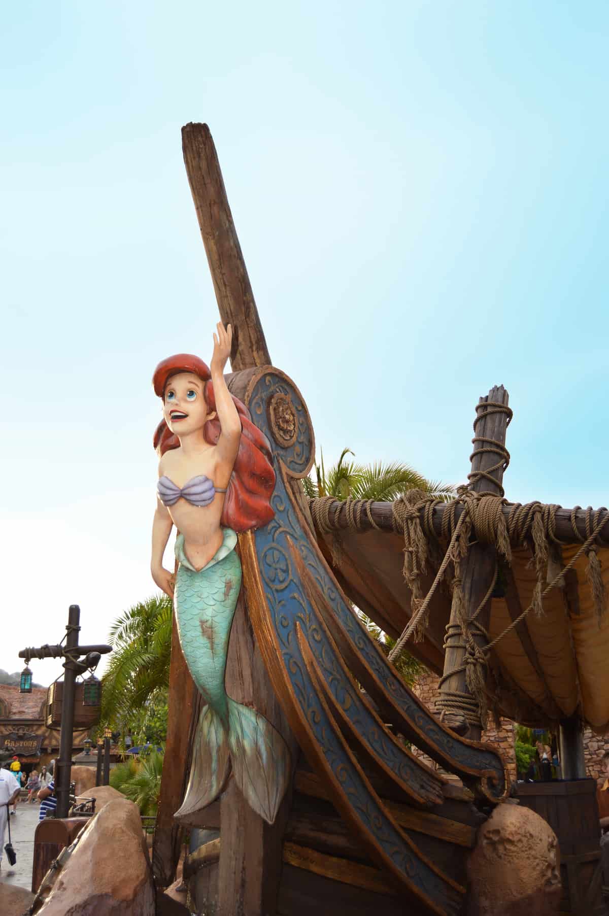 Ariel, the Little Mermaid, perched on a ship’s prow, delights Magic Kingdom guests beneath the iconic Florida sunshine.