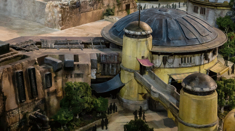 A futuristic model of domed buildings with trees and guests, evoking the Star Wars: Galaxy’s Edge atmosphere at Disney parks.