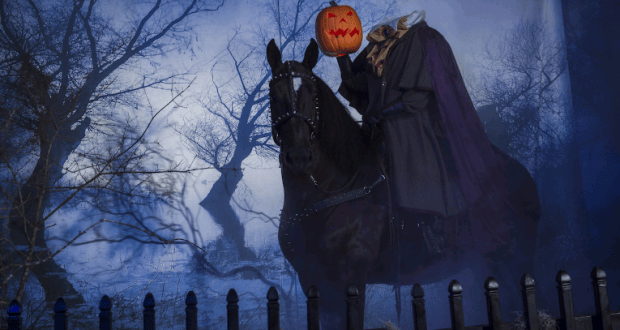 The Headless Horseman on a black horse rides through Sleepy Hollow’s haunted, fog-filled woods during the Halloween attraction.