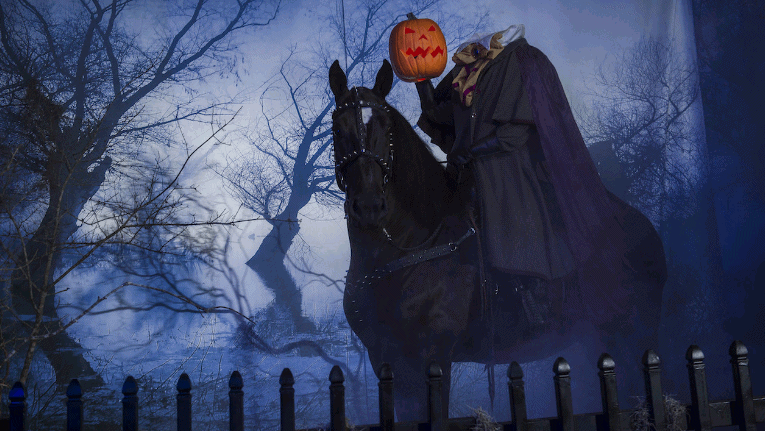 The Headless Horseman on a black horse rides through Sleepy Hollow’s haunted, fog-filled woods during the Halloween attraction.