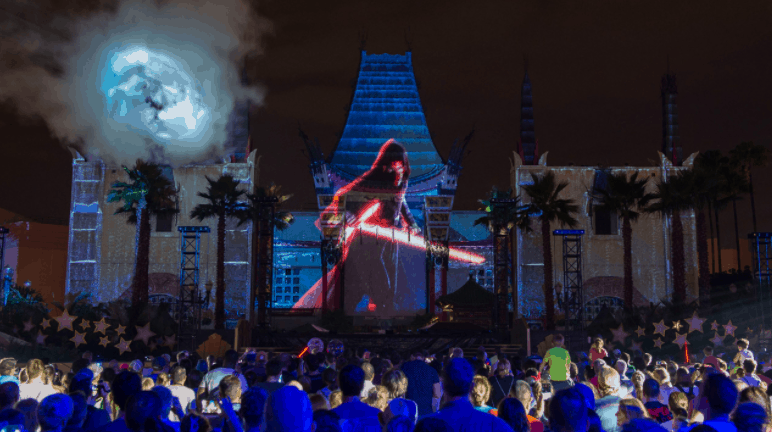 Guests gather at Disney’s Star Wars: Galactic Nights as a red lightsaber lights up the night with dazzling building projections.