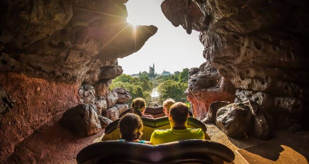 Guests thrill on Splash Mountain at Walt Disney World, racing through a rocky tunnel toward Cinderella Castle in bright sunshine.