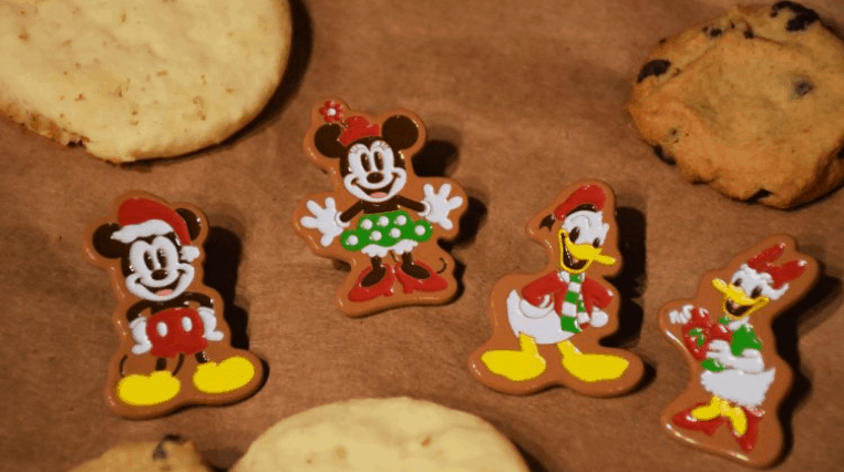 Mickey, Minnie, Donald, and Goofy gingerbread pins and cookies line a table—must-haves for Disney holiday pin collectors.