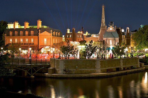 Parisian nightscape at EPCOT with glowing Eiffel Tower replica, elegant lit facades, and shimmering lagoon—ultimate Disney date spot.