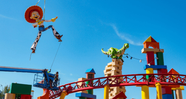 Jessie and Rex decorations soar above the Slinky Dog Dash coaster in Toy Story Land, all set against a vibrant blue sky.