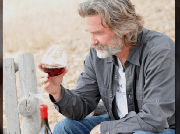 A DVC Member with gray hair and a beard samples red wine outdoors, savoring the magic of Walt Disney World in a special moment.