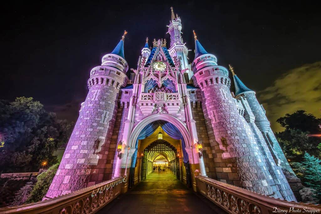 Cinderella Castle glows with vibrant lights at Magic Kingdom’s entrance, creating a magical Disney World nighttime welcome.