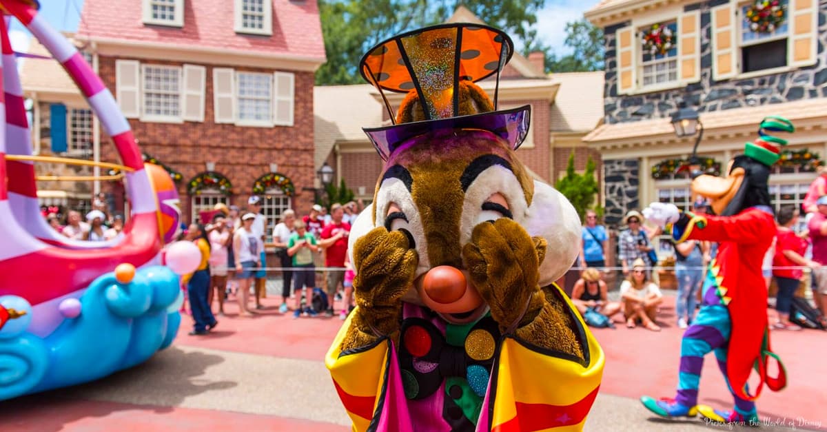 Chip and Dale, dressed in vibrant parade costumes, playfully cover their eyes while delighting Disney World parade guests.