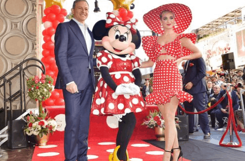 A dapper guest, Minnie Mouse, and a woman in a red polka-dot dress shine on the Walt Disney World red carpet.