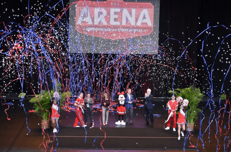 Fans cheer onstage as confetti and streamers fly under the glowing "The Arena" sign at ESPN Wide World of Sports Complex.