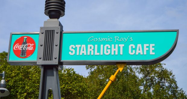 Cosmic Ray’s Starlight Cafe turquoise sign with Coca-Cola logo pops against a blue sky at Walt Disney World—fan-favorite eatery.