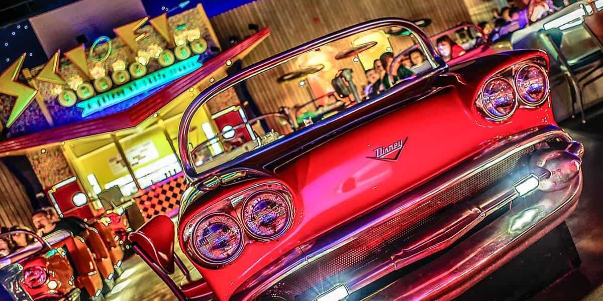 A classic red car booth at Sci-Fi Dine-In Theater in Disney World, with guests enjoying their meals under retro movie lights.