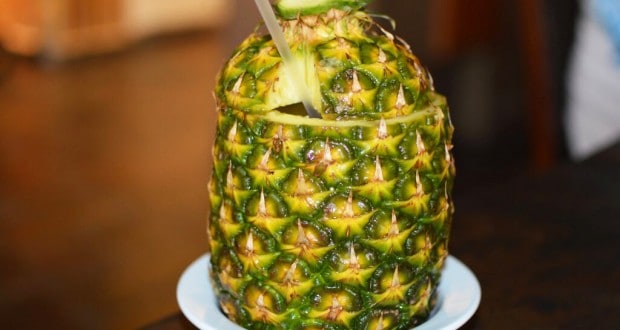 A pineapple with the top off, filled with a tropical drink and straw, just like you’d enjoy at Disney’s Tambu Lounge.