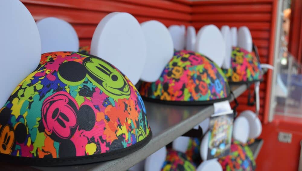 Vibrant Mickey Mouse ear hats with white ears line shelves beneath a bold red wall inside Disney World's magical shops.