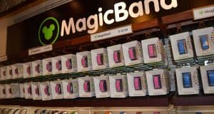 MagicBands in a rainbow of Disney designs line the shelves beneath a MagicBand sign, ready for your next park adventure.