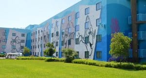 Blue Disney hotel with lively cartoon fish murals, lots of windows, and lush green grass—ideal for budget-savvy parkgoers.