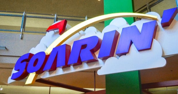 Soarin'" sign with bold letters and clouds, glowing inside Epcot with themed lighting and railings at Walt Disney World.