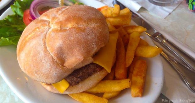 A classic Disney World cheeseburger with lettuce, tomato, and fries on a white plate—served with fork and knife for theme park magic.