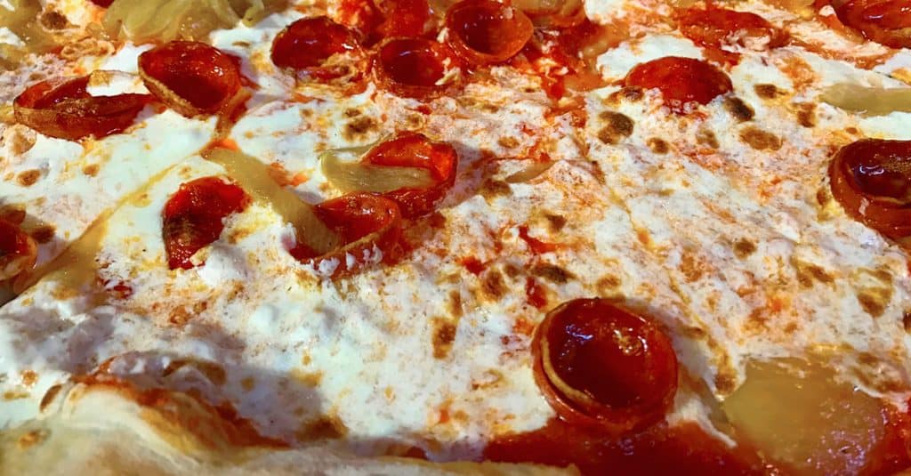 Close-up of a Disney World pizza featuring pepperoni, gooey cheese, zesty sauce, and pineapple—perfect for your Dining Plan.