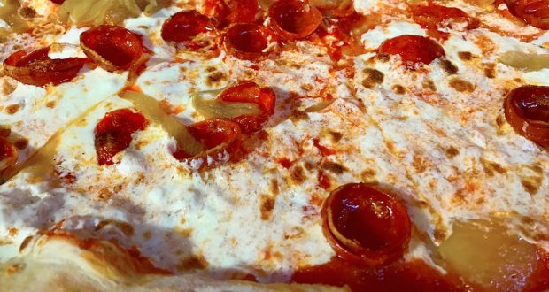 Close-up of a Disney World pizza featuring pepperoni, gooey cheese, zesty sauce, and pineapple—perfect for your Dining Plan.