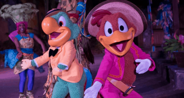 José and Panchito dance in vibrant costumes onstage at the lively Discovery Island Carnivale, joined by energetic performers.