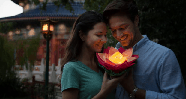 Guests celebrate Lunar New Year at Walt Disney World, holding a glowing lotus lantern for the perfect nighttime photo moment.