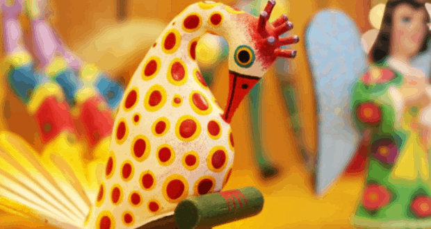 Oaxacan-style wooden bird with red spots, yellow wings, and red beak, echoing vibrant Coronado Springs Resort decor at Disney World.