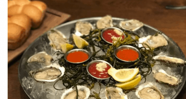 Celebrate your 1st Anniversary at Paddlefish, Walt Disney World with fresh oysters on ice, lemon wedges, and sauces; bread rolls behind.